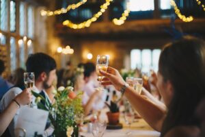 A couple reviews a long guest list at a table inside a spacious decorated event hall.